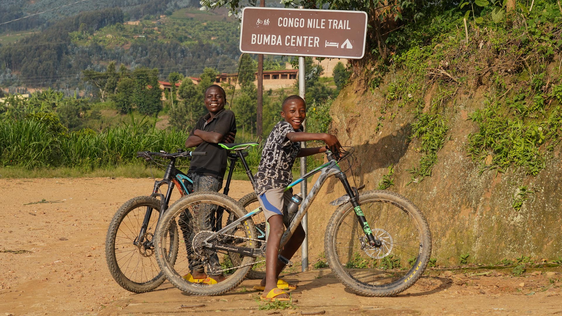 2 enfants à vélo devant le panneau du Congo Nile Trail au Rwanda