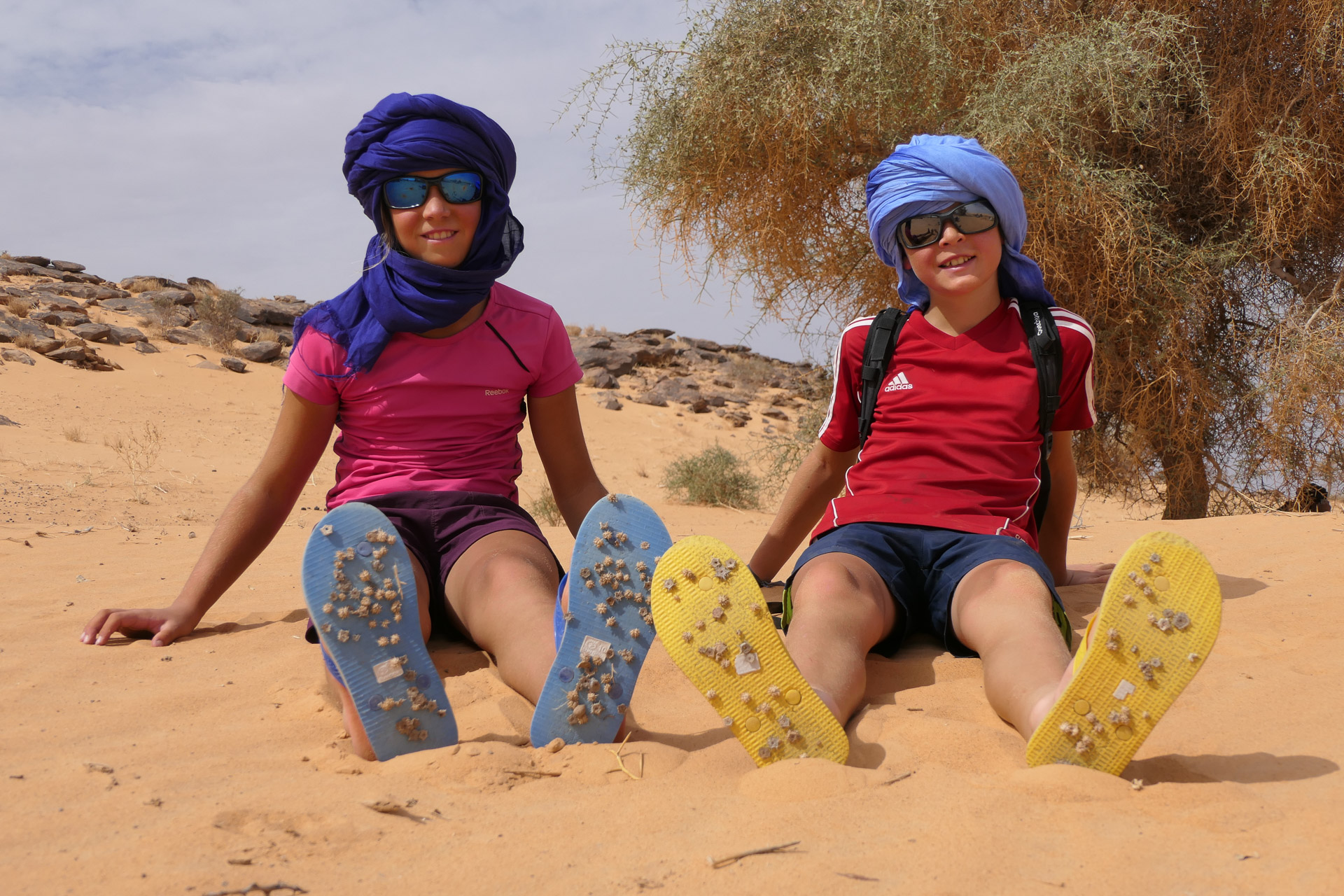 2 enfants dans le désert, avec des piquants dans les tongs