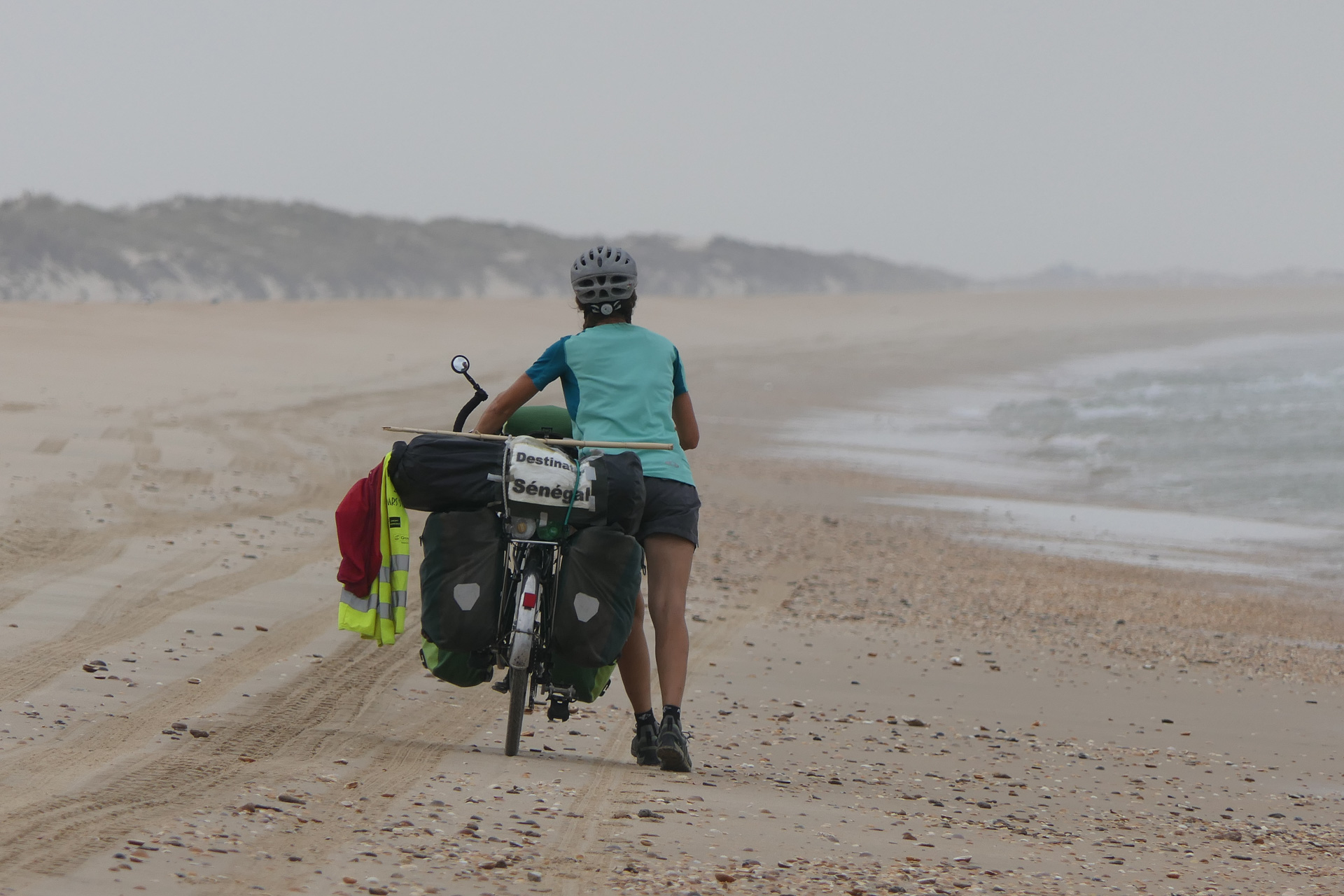 voyageuse poussant son vélo sur la plage
